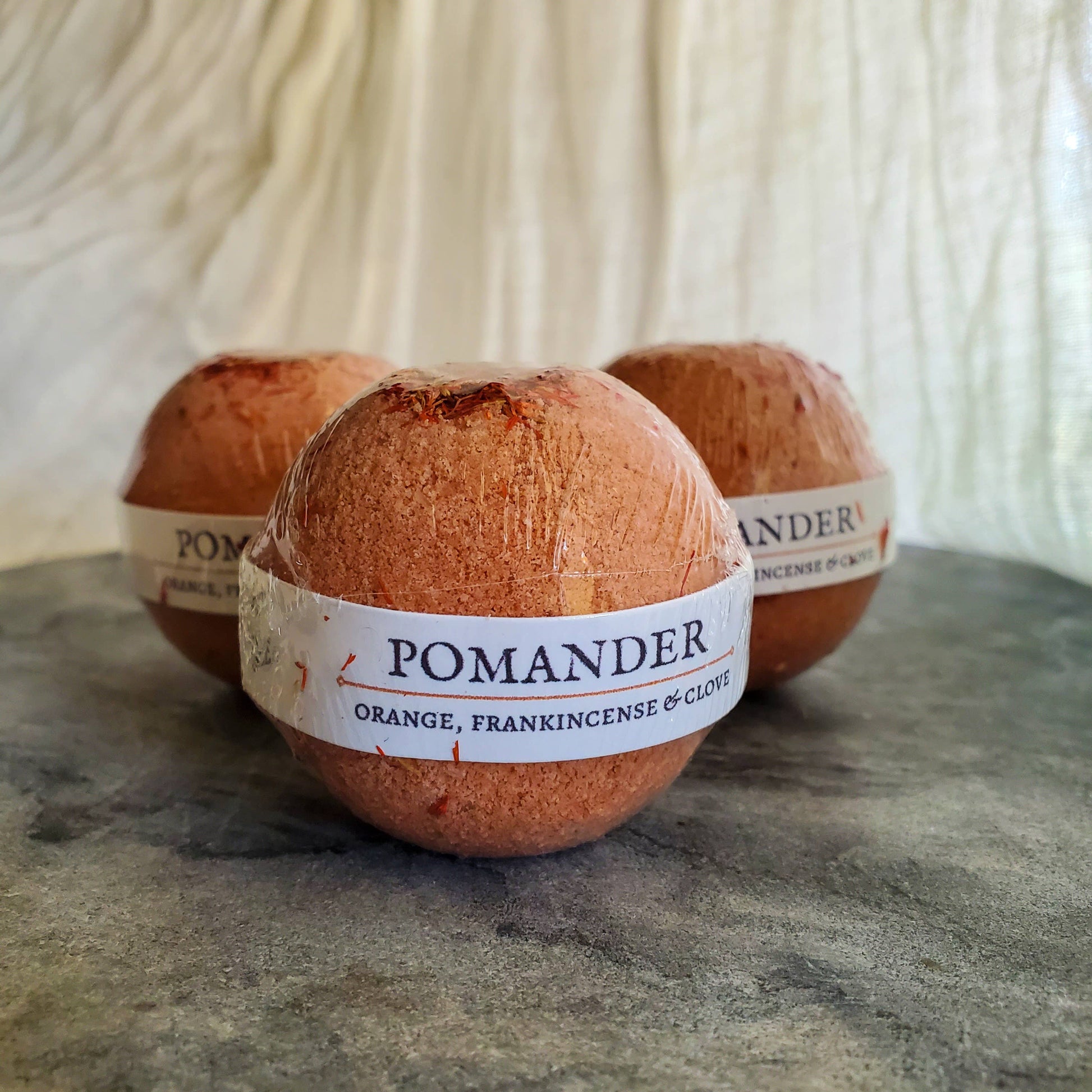 Pomander Bath Bomb, medium size with warm, seasonal scents of wild orange, frankincense, and clove, perfect for grounding and relaxation in bath rituals. Packaged Photo.
