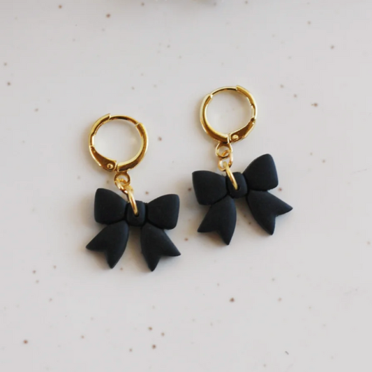 A pair of handmade Black Bow Huggie Earrings made from lightweight polymer clay with 18k gold-plated hardware, hypoallergenic and nickel-free.